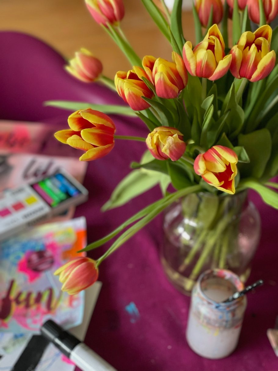 Artist’s workspace with tulips, paper studies, and oil pastels on the table